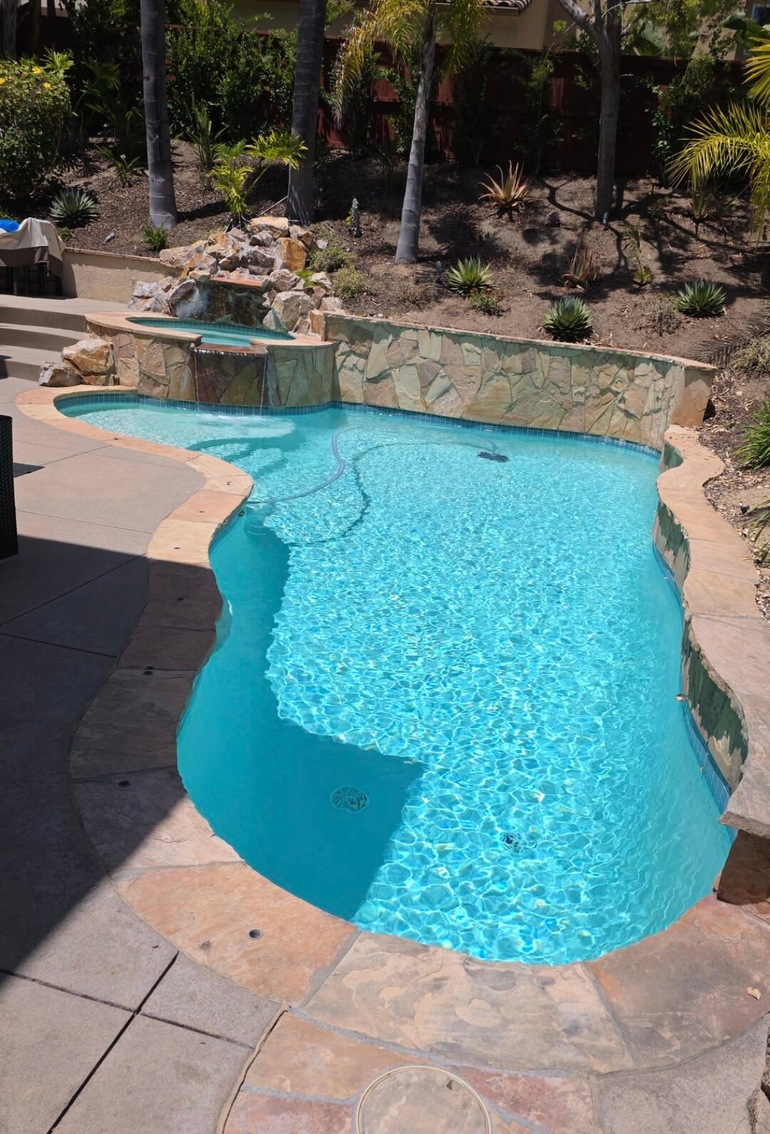 Custom backyard pool with waterfall feature by Gaxiola Pools Inc.